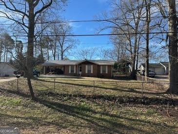Ranch style home with a metal roof and mature trees in the front yard at 360 Meadowbrook Dr, Mcdonough, GA 30253