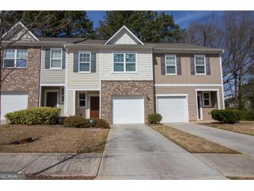 Charming townhome showcasing varied exterior finishes and attached garages with paved driveways at 6342 Kinsland Ct, Lithonia, GA 30058