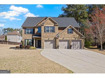 Traditional brick home with a three-car garage and a well-manicured front lawn on a sunny day at 2441 Noelle Ln, Powder Springs, GA 30127