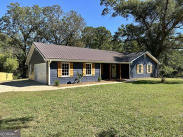 Charming single-story home featuring a metal roof, yellow shutters, and a well-manicured lawn at 3280 Gum Creek Rd, Oxford, GA 30054