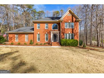 Traditional red brick home with a well-manicured lawn and mature trees in a suburban setting at 423 Holly Grove Church Rd, Peachtree City, GA 30269