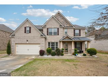 Two-story brick home with attached garage, manicured landscaping, and covered front porch at 3225 Alhambra Cir, Hampton, GA 30228