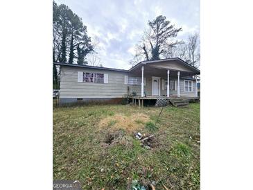 Modest single story home with covered porch and light gray siding needs TLC at 9135 Ford Sw St, Covington, GA 30014