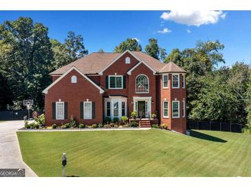 Stunning two-story brick home boasts lush landscaping and a well-manicured lawn under a bright, partly cloudy sky at 3015 Gold Creek Dr, Villa Rica, GA 30180