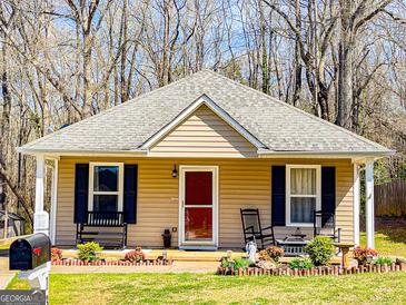 Charming home with a red front door, rocking chairs on the porch, and well-maintained landscaping at 136 Glynn Addy Dr, Stockbridge, GA 30281