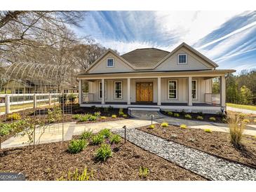 Charming home with a welcoming front porch, complemented by a beautifully landscaped yard and an elegant arched walkway at 721 Wedowee St, Bowdon, GA 30108