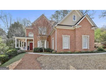 Charming red brick home featuring a covered porch and well-manicured landscaping at 300 The Enclave, Peachtree City, GA 30269