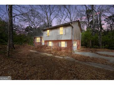 Two-story home featuring a brick and vinyl exterior, nestled in a wooded landscape with an attached garage at 40 Derby Country Dr, Ellenwood, GA 30294