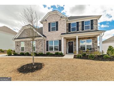 Two story home with brick and stone exterior, black shutters, covered porch, and landscaped front yard at 814 Parker Pass, Peachtree City, GA 30269