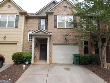 Inviting brick townhome with well-manicured landscaping, a one-car garage, and a charming covered entrance at 2742 Keystone Gates Ct, Lithonia, GA 30058