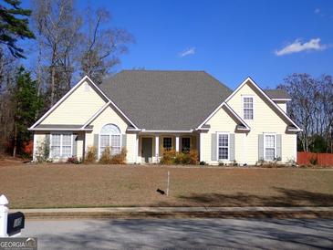 Charming single-story home features a symmetrical design, complemented by gray shutters and a lush front lawn at 180 Sunderland Cir, Fayetteville, GA 30215