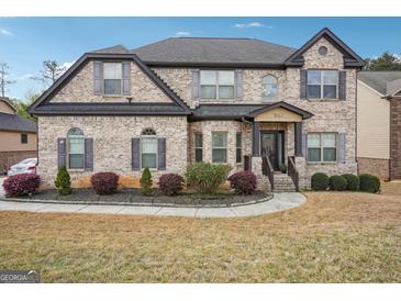 Two-story brick home features a well-manicured lawn and a welcoming front porch with decorative columns at 3863 Rosebay Way, Conyers, GA 30094