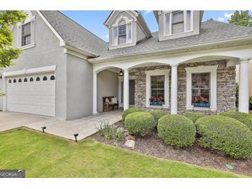 Charming home featuring a stone facade, white pillars, tidy bushes, and well manicured landscaping at 211 Collierstown Way, Peachtree City, GA 30269