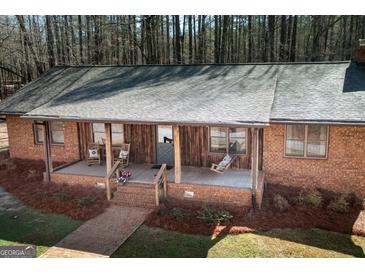 Charming brick home featuring a cozy front porch with rocking chairs and rustic wood accents at 222 Providence Rd, Fayetteville, GA 30215