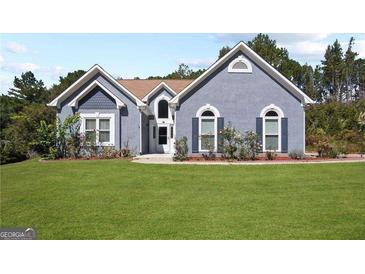 Charming blue stucco home featuring a lush green lawn and well-maintained landscaping at 131 Pecan Lake Dr, Sharpsburg, GA 30277