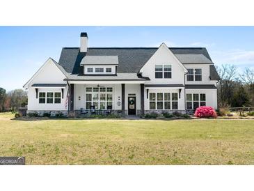 Charming two-story home featuring a black front door, white siding, rocking chairs, and a well-maintained lawn at 105 Coogler Way, Brooks, GA 30205
