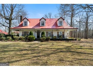 Charming two-story home featuring a red metal roof, dormer windows, and a spacious front yard at 680 Milligan Creek Rd, Roopville, GA 30170