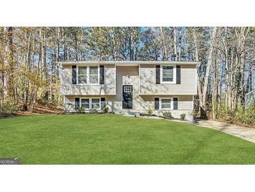 Charming two-story home with green lawn, black shutters, and lush trees at 1897 Madras Ct, Lithonia, GA 30058