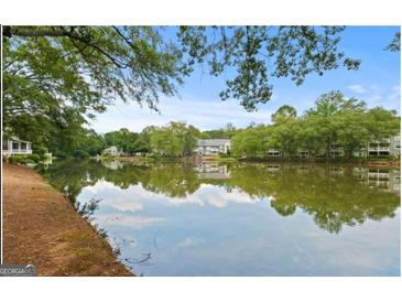 Scenic lake view with mature trees and reflections of community houses enhancing natural beauty at 402 Mill Pond Rd # 402, Roswell, GA 30076