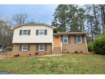 Charming split-level home featuring a bright, welcoming door and manicured lawn at 203 Greensprings Dr, Palmetto, GA 30268