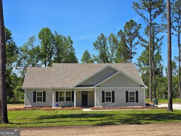 Charming single-story home featuring a manicured lawn and inviting entrance, nestled among mature trees under a clear sky at 22638 Salem Church Rd, Metter, GA 30349