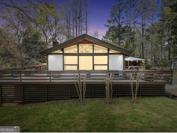 Charming home featuring a large deck and expansive windows, creating a welcoming facade at dusk at 509 Eskew Rd, Mcdonough, GA 30252