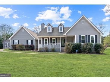 Charming home featuring a well-manicured lawn and inviting front porch with black shutters and a detached garage at 280 Nutt Dr, Locust Grove, GA 30248