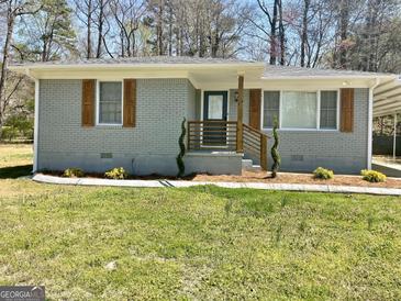 Charming gray brick home featuring stylish wooden shutters and a quaint front porch at 103 Greenwood Dr, Stockbridge, GA 30281