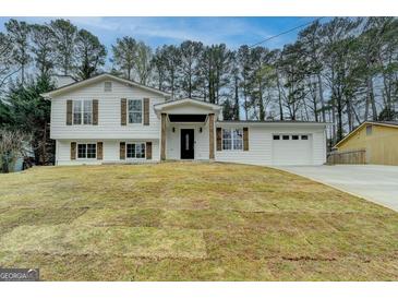 Charming split-level home featuring a fresh white exterior, rustic shutters, and attached two-car garage at 5155 Rosestone Nw Dr, Lilburn, GA 30047