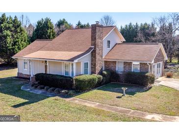 Charming two-story home with brick chimney, manicured lawn, and mature trees at 105 Overlook Dr, Mcdonough, GA 30252