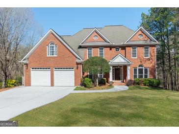 Beautiful two-story red brick home with a manicured lawn, large driveway and attached two car garage at 140 Longwater Cv, Roswell, GA 30075