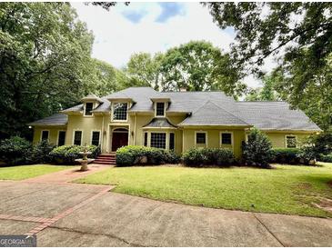 Traditional home featuring a lush lawn, mature trees, and a circular driveway with a decorative fountain at 115 Flagstop Run, Fayetteville, GA 30215