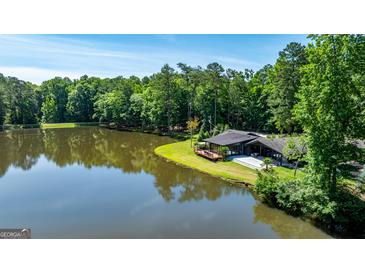 Stunning lakeside home with a deck overlooking the water, surrounded by lush trees and blue sky at 129 Old Norton Rd, Fayetteville, GA 30215