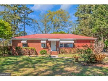Charming brick ranch-style home featuring a red metal roof and a well-maintained front yard at 111 Highway 138 E, Stockbridge, GA 30281