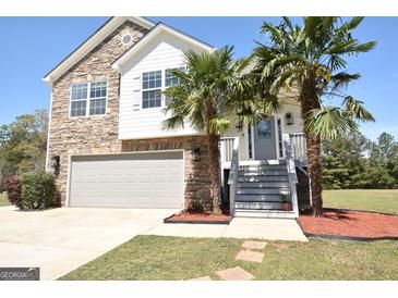 Charming two-story home featuring stone accents, a front-facing garage, and lovely palm trees flanking the entrance at 116 Ducati Dr, Mcdonough, GA 30252