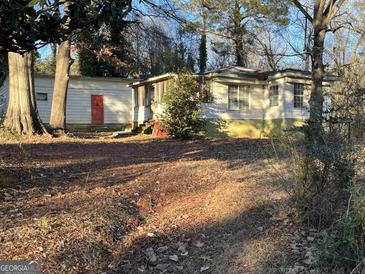 Exterior view of a single-story home with a red door, situated on a tree-filled lot at 65 Little John Trl, Hampton, GA 30228