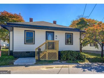 Charming single-Gathering home featuring white siding, black trim, and a cozy front porch with a wooden railing at 34 Ivy St, Porterdale, GA 30014