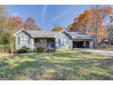 Charming single-story home with a cozy front porch and a convenient carport, surrounded by colorful autumn foliage at 106 Kirkland Rd, Covington, GA 30016