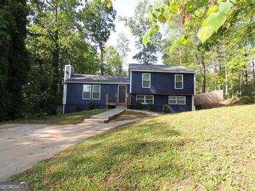 Charming two-story home featuring a well-manicured front yard with lush trees and a concrete driveway at 851 Bridgewater Ct, Stone Mountain, GA 30088