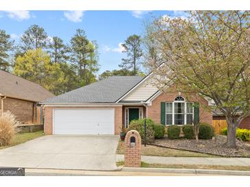 Charming one-story brick home featuring an attached garage and a well-maintained front yard with mature landscaping at 2733 Newtons Crest Cir, Snellville, GA 30078
