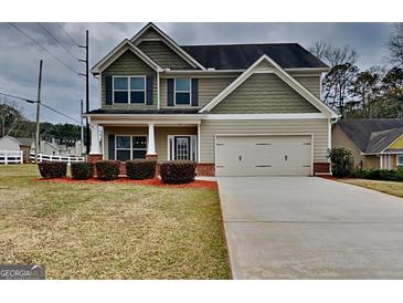 Charming two-story home with green siding, a two car garage, and well manicured landscaping at 483 Castle Top Ln, Lawrenceville, GA 30045