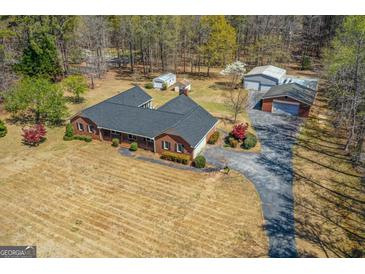 An inviting brick home features a long driveway, a spacious yard, and several outbuildings perfect for storage at 426 Old Senoia Rd, Fayetteville, GA 30215