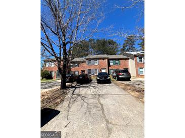 Brick townhouse complex with a gray concrete driveway and sparse winter landscaping at 8023 Creekstone Way, Riverdale, GA 30274
