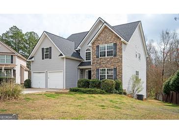 Charming two-story home featuring a stone facade, gray siding, and an attached two-car garage at 347 Cobblestone Ct, Hampton, GA 30228