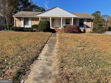 Charming one-story brick home with inviting front porch and mature landscaping at 6099 Winview Dr, Forest Park, GA 30297