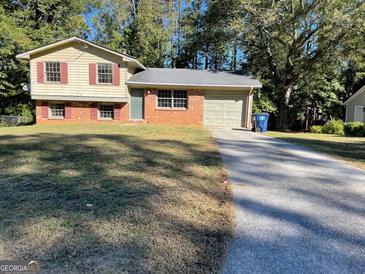 Split-level home with a brick facade, siding, attached garage and a spacious driveway on a sunny day at 6332 Valley Dale Dr, Riverdale, GA 30274