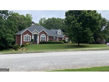 Charming brick home with lush green lawn, mature trees, and manicured landscaping providing excellent curb appeal at 9039 River Bend Ct, Villa Rica, GA 30180
