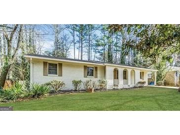 Charming ranch-style home featuring a white brick exterior, well-maintained lawn, and mature trees providing shade at 767 San Miguel Dr, Stone Mountain, GA 30083