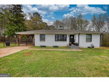 Charming home featuring white brick, black trim, lovely lawn, and covered parking at 1910 Reese Rd, Rutledge, GA 30663