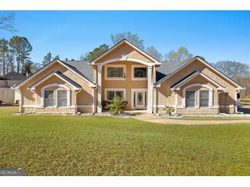Stunning two-story home featuring a lush green lawn, a symmetrical facade, and a welcoming entrance on a sunny day at 90 Hazelridge Ln, Sharpsburg, GA 30277
